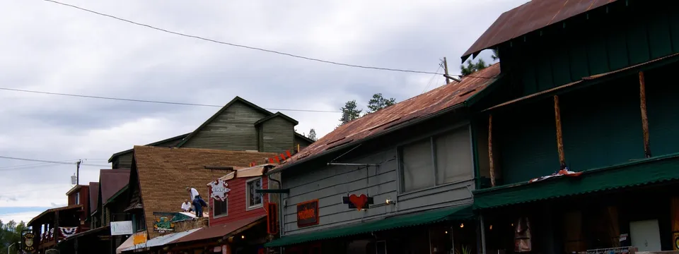 Downtown Evergreen on Highway 74: wooden storefronts with tin roofs and awnings, pickups parked along the boardwalk